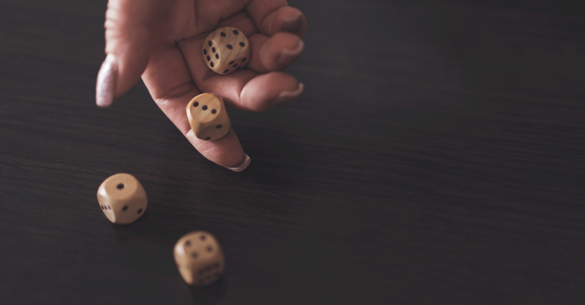 A close-up view of a hand rolling wooden dice on a dark wooden surface, showcasing a classic gaming moment.